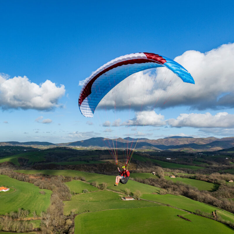 blauer Gleitschirm vor Wolken